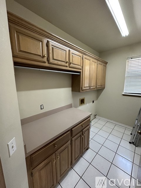 A kitchen with wooden cabinets and white tiled flooring.