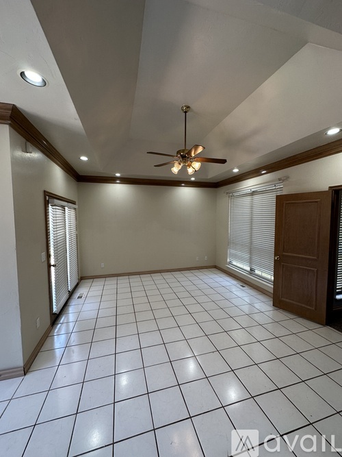 A spacious room with a ceiling fan and tiled flooring.