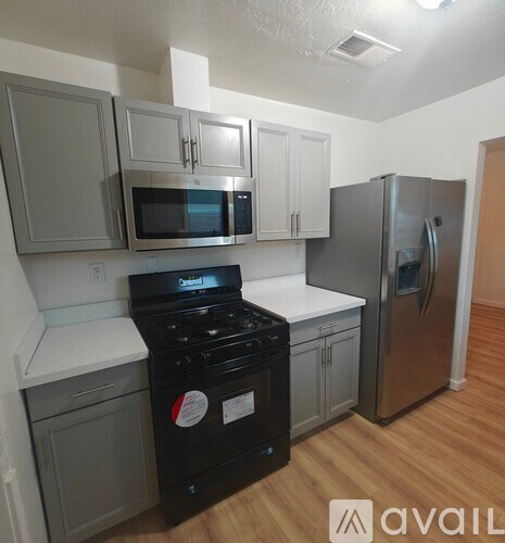 A kitchen with a black stove top oven and a refrigerator.