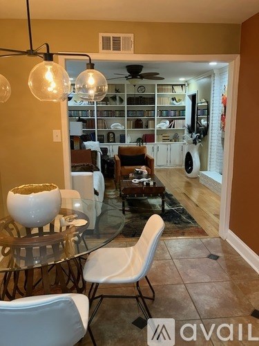 A living room with a glass table and white chairs.