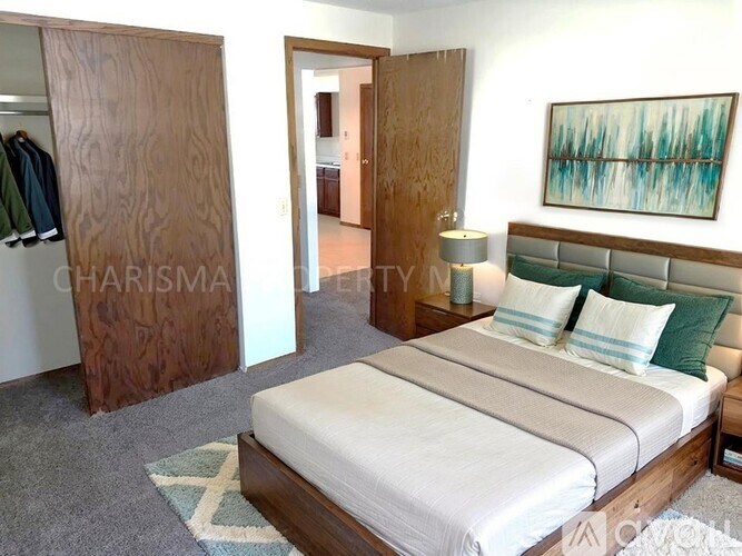 A bedroom with a large bed and a painting on the wall.