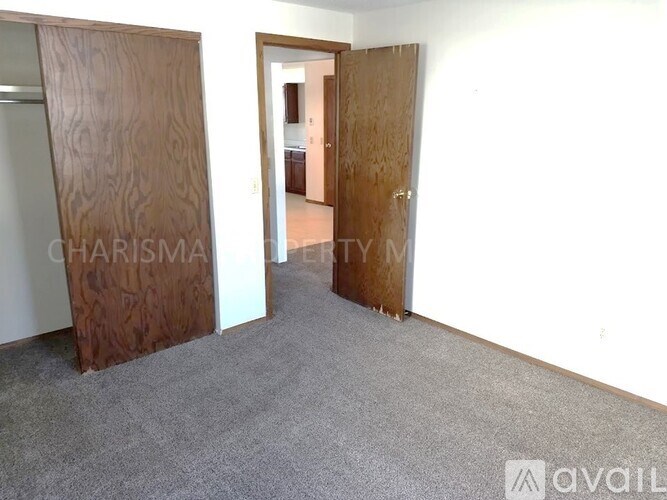 A room with a carpeted floor and two wooden doors.