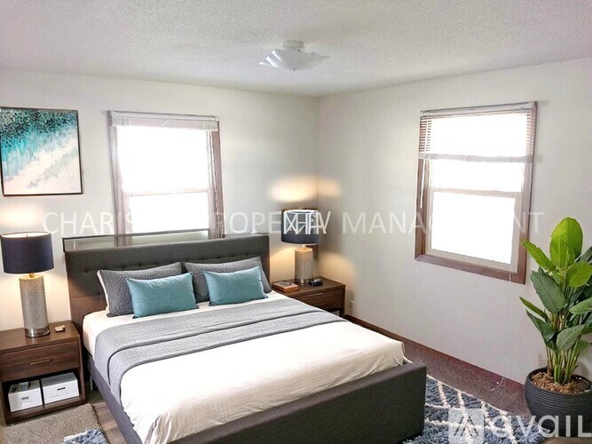 A bedroom with a bed, nightstand, and a plant.