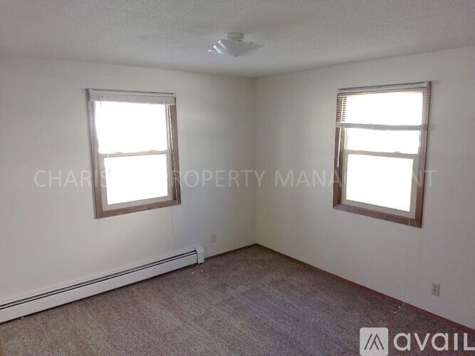 A room with two windows and carpeted floor.