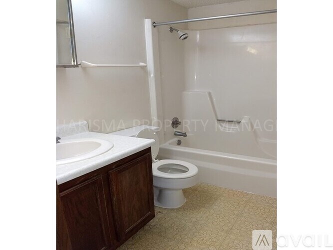 A white toilet is in a bathroom with a sink and a bathtub.