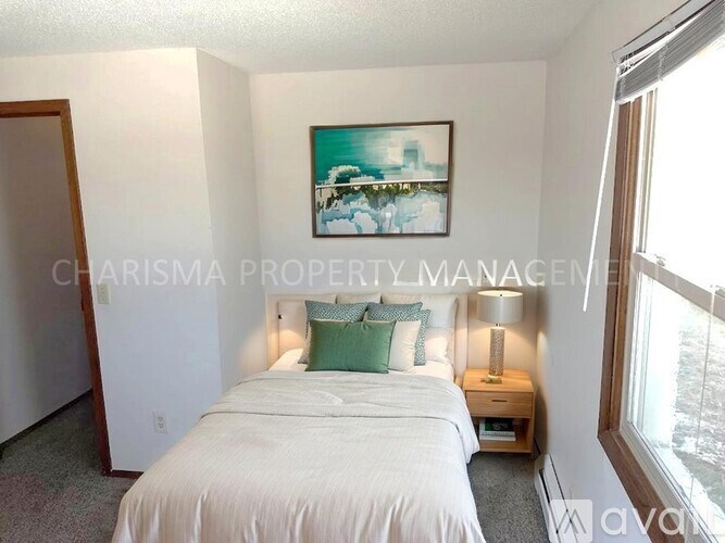 A bedroom with a bed, nightstand, and a painting on the wall.