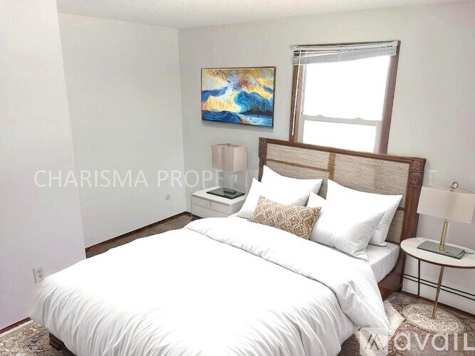 A bedroom with a large bed, a nightstand, and a painting on the wall.