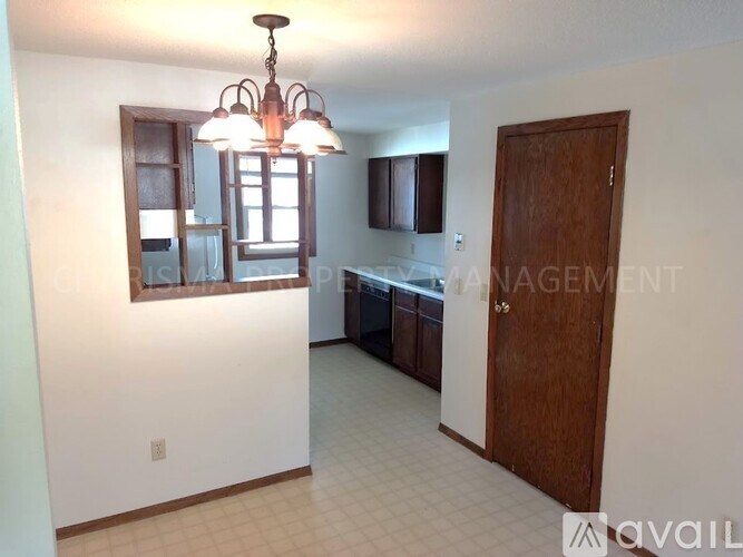 A well-lit room with a chandelier, a window with a view, and a door leading to another room.
