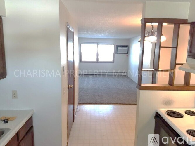 A kitchen with a stove top oven and a doorway leading to a bedroom.