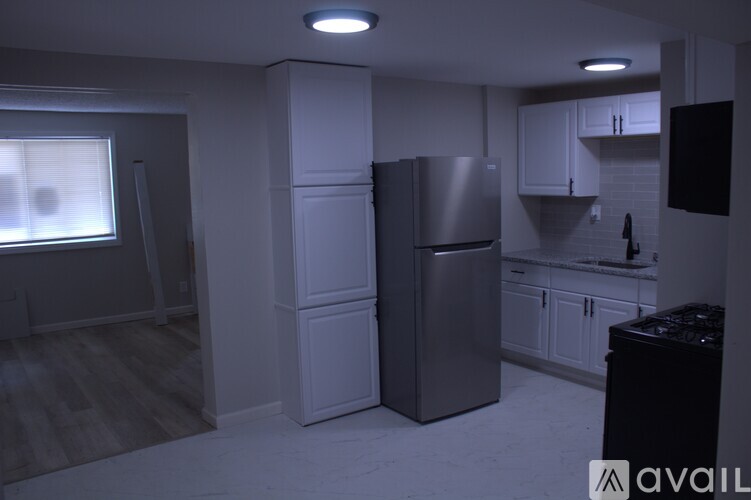 A kitchen with a refrigerator, cabinets, and a countertop.