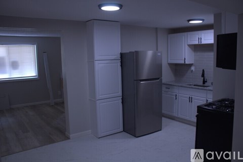 A kitchen with a refrigerator, cabinets, and a countertop.