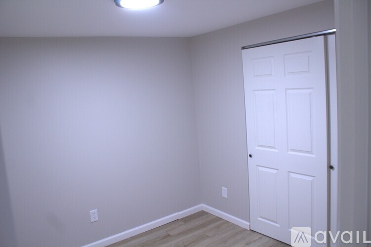 A white door is on the right side of a room with a light on the ceiling.