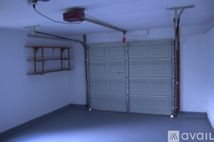 A garage with a closed door and a shelf on the wall.