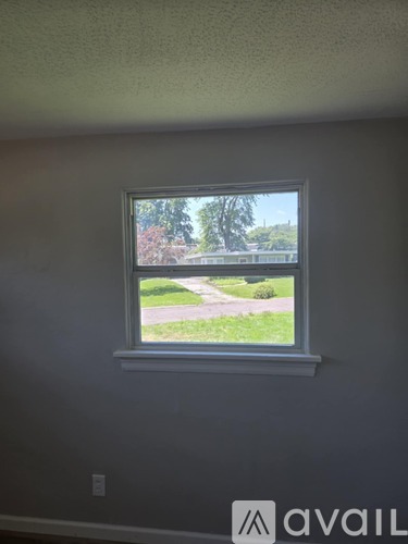 A window in a room with a view of a street and trees.