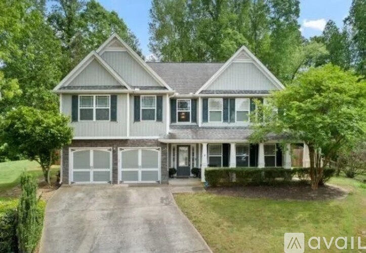 A two-story house with a garage is surrounded by trees.