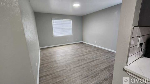 A room with wooden flooring and a window with blinds.