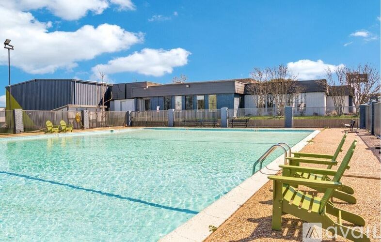 A swimming pool with green chairs and a building in the background.