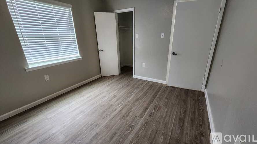 A room with wooden flooring and a window with blinds.