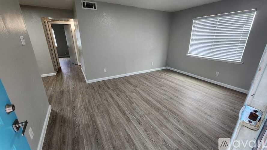 A room with wooden flooring and a door leading to another room.