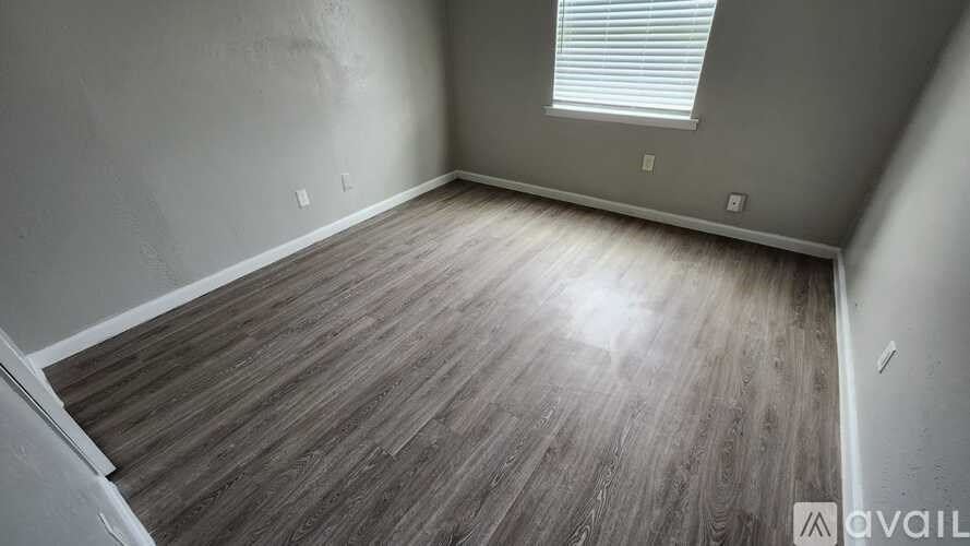 A room with wooden flooring and a window with blinds.
