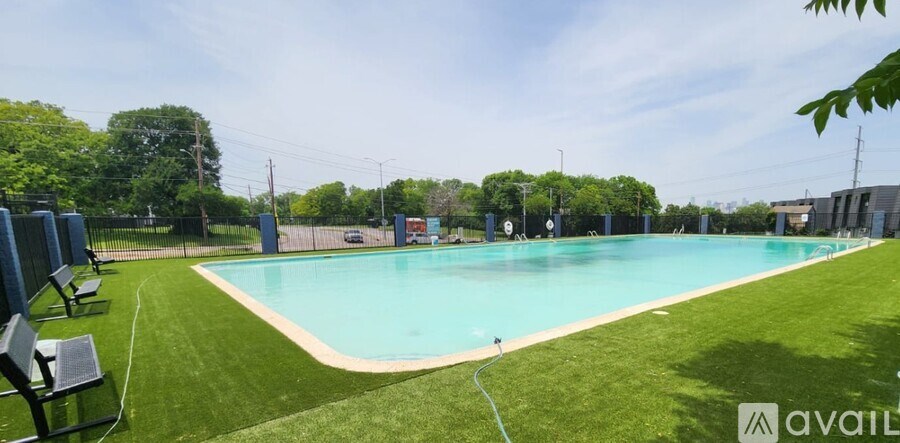 A large outdoor swimming pool surrounded by a grassy area and trees.