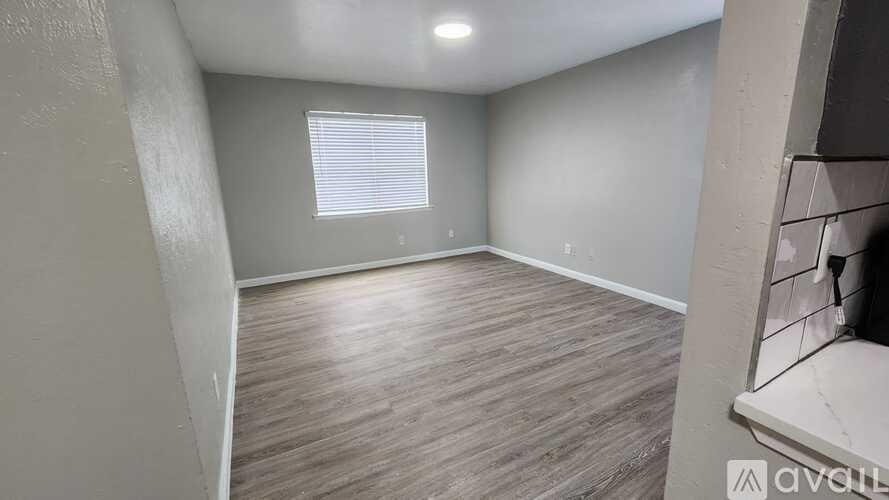 A room with wooden flooring and a window with blinds.