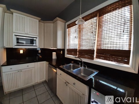 A kitchen with white cabinets and a black countertop.