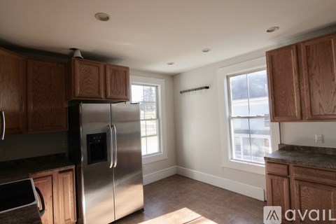 A kitchen with wooden cabinets and a stainless steel refrigerator.