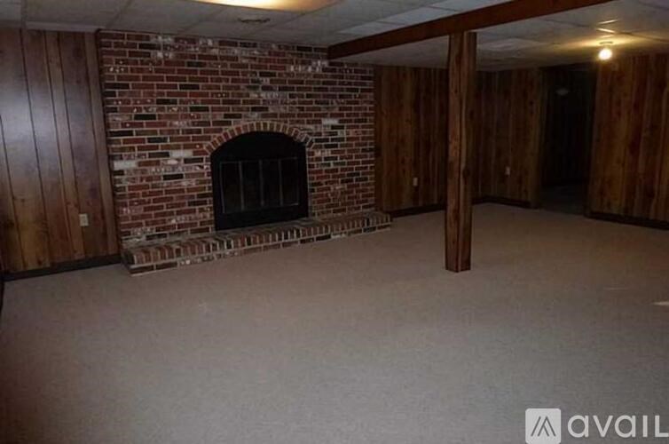 A room with a brick fireplace and wooden walls.