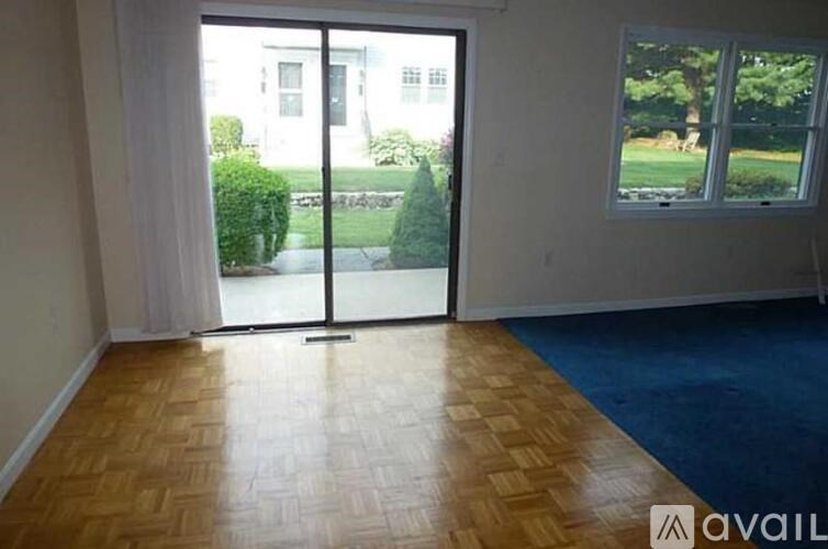 A room with a wooden floor and a sliding glass door leading to a garden.
