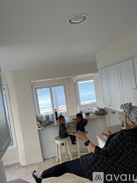 A woman is sitting on a chair in a kitchen with a child on her lap.