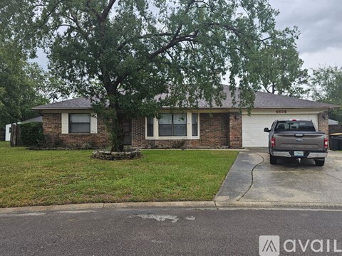 A house with a tree in front and a truck parked in the driveway.