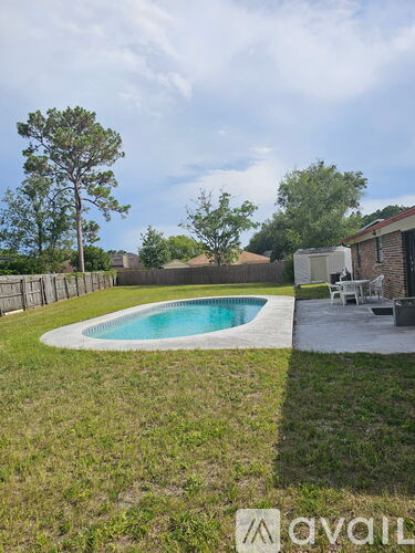 A pool in a backyard with a white chair and a house in the background.