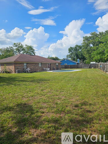 A grassy yard with a house and a fence.