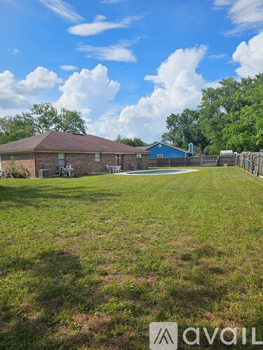 A grassy yard with a house and a fence.