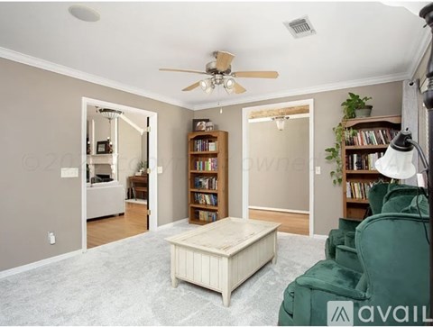 A living room with a green couch and a white ottoman.