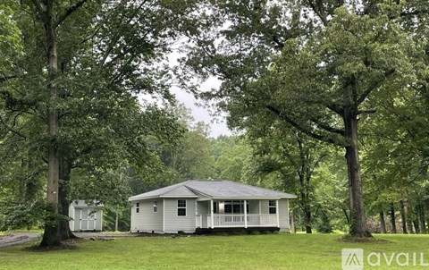 A house surrounded by trees in a grassy area.