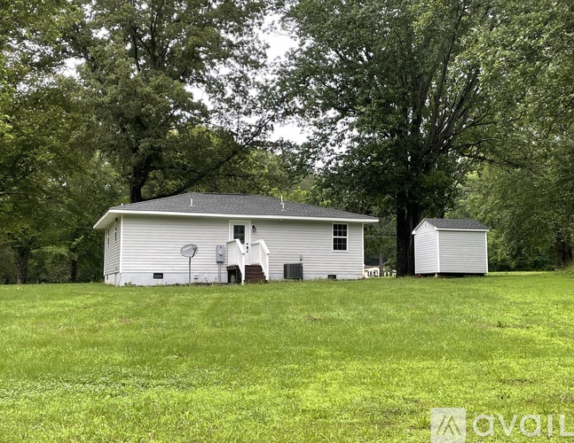 A white house with a grey roof is surrounded by a green field.
