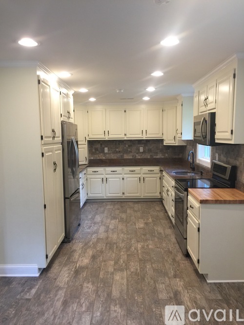 A kitchen with white cabinets and a wooden island.