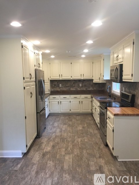 A kitchen with white cabinets and a wooden island.