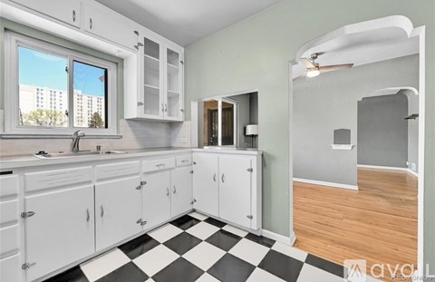 A kitchen with white cabinets and a black and white checkered floor.