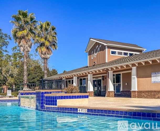 A pool with a building and palm trees in the background.