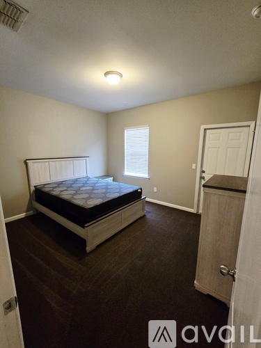 A bedroom with a bed, dresser, and window.