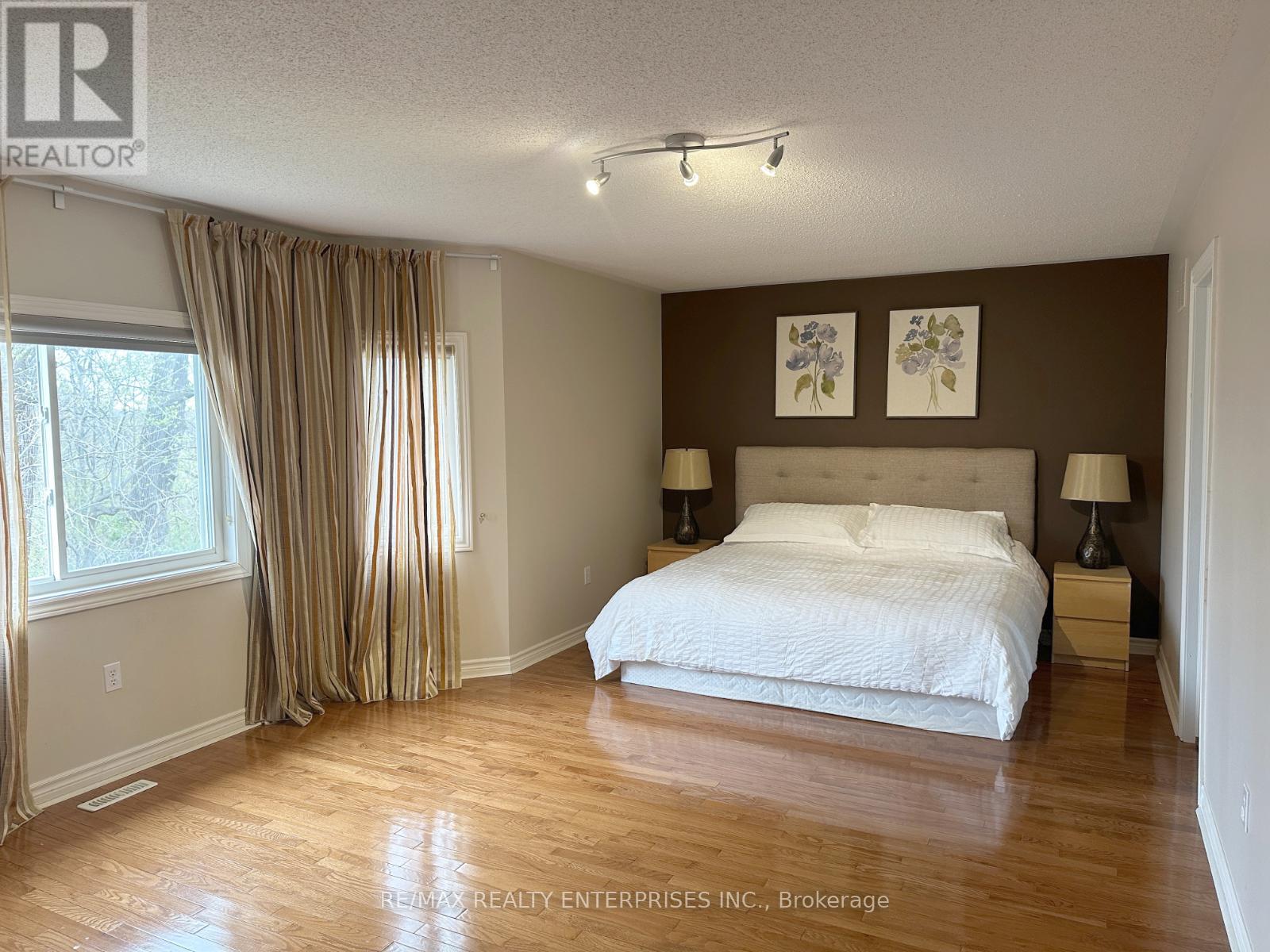 A bedroom with a large bed and wooden floors.