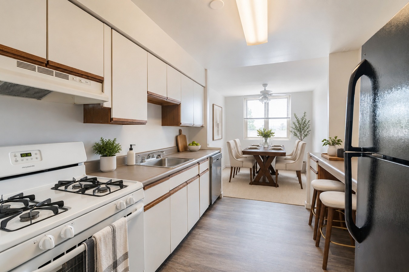 A modern kitchen with a black refrigerator, white cabinets, and a dining area with a table and chairs.