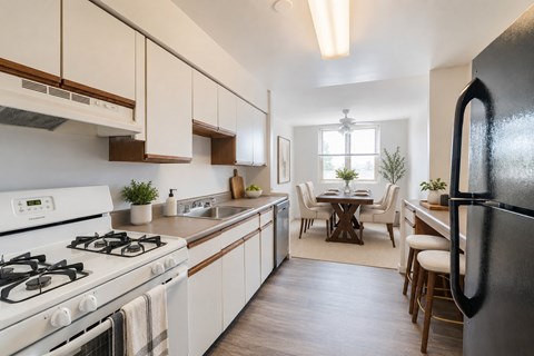 A modern kitchen with a black refrigerator, white cabinets, and a dining area with a table and chairs.