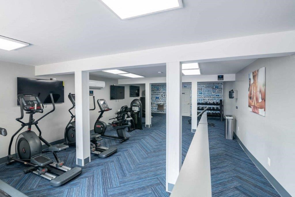a gym in the basement of a home with weights and a tv
