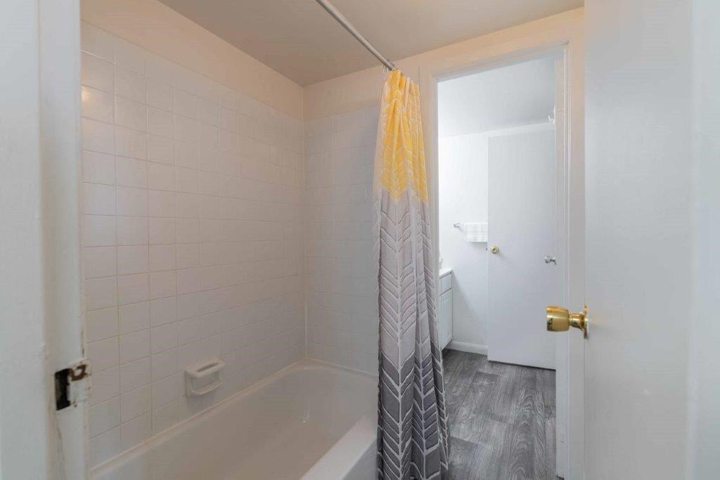 a white bathroom with a shower curtain and a tub