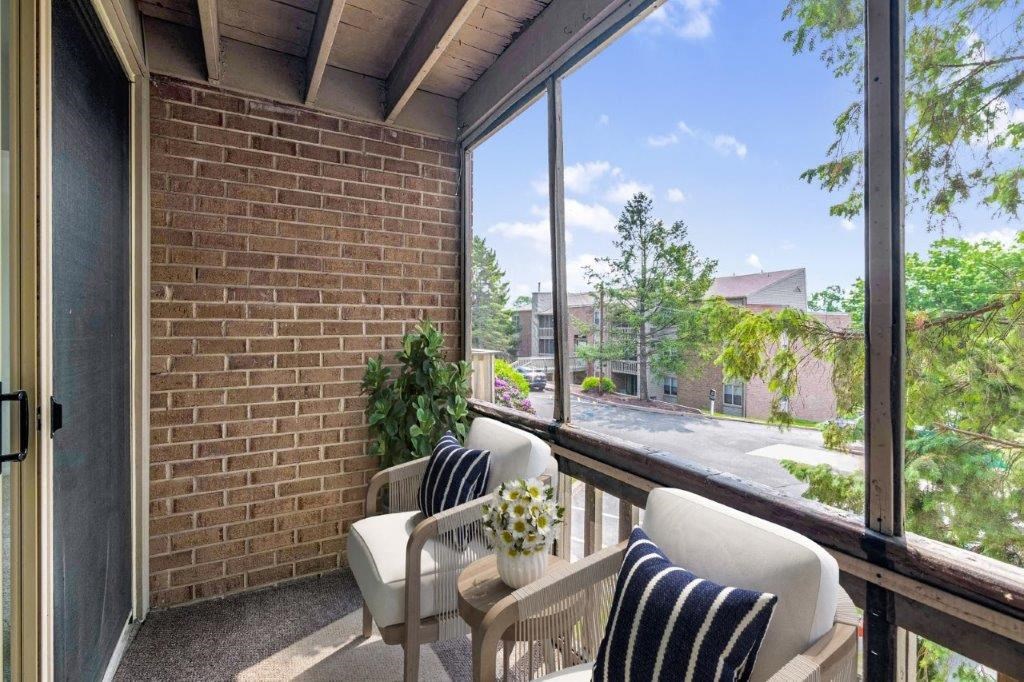 a porch with two chairs and a table and a large window