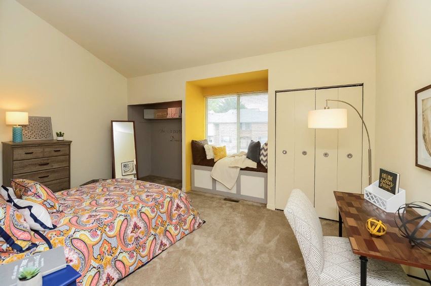 a bedroom with a bed and a desk and a window